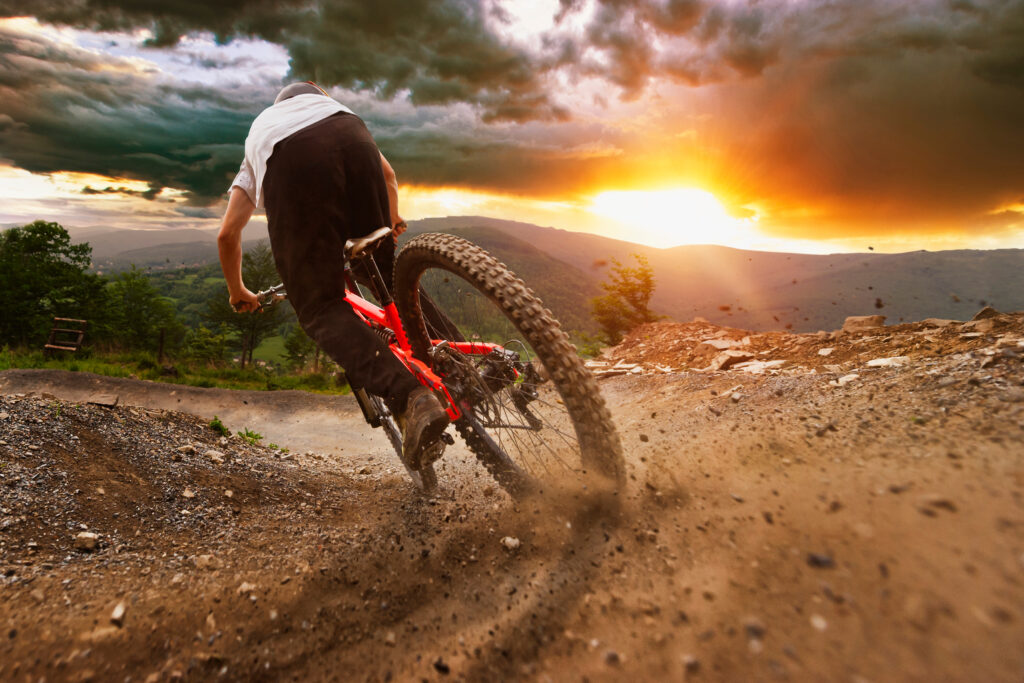 Man on mountain bike rides on the trail on a stormy sunset.